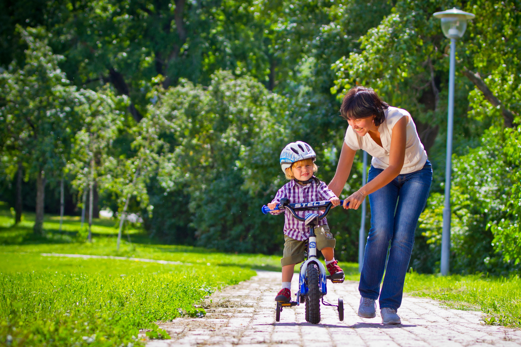 Как арендовать ребенка. Мама учит ребенка кататься на велосипеде. В чем катают малышей на улице летом.